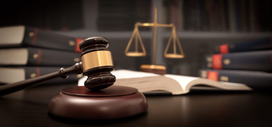 Judge gavel and scale in court. Library with lot of books in background