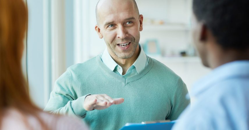 Portrait of mature business manager instructing young trainees during internship in office, copy space